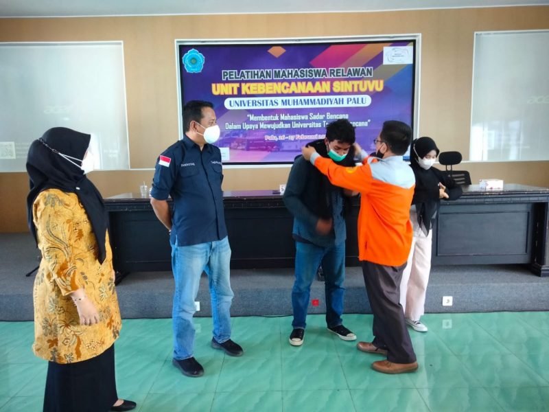 Rektor Unismuh Palu Prof. Dr. H. Rajindra, SE., MM saat memasangkan atribut kepada salah satu peserta pelatihan.