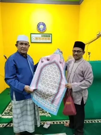 Rektor Unismuh Palu, Prof Dr. H. Rajindra, SE., MM saat menyerahkan cenderamata berupa sajadah kepada pengurus masjid. Foto: Humas